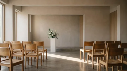 Salle de cérémonie funéraire épurée baignée de lumière douce, évoquant un moment de recueillement silencieux